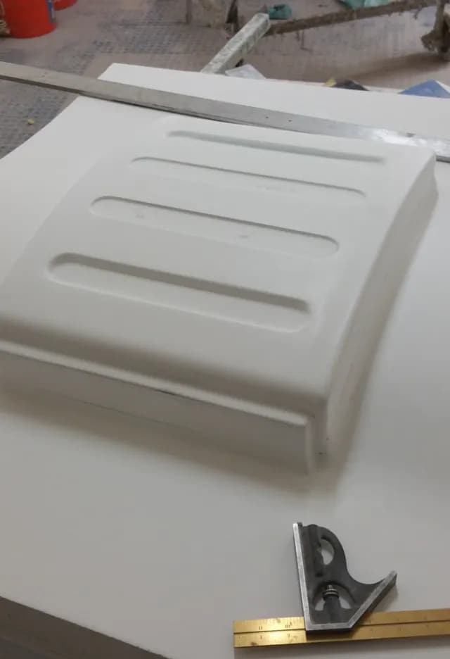 White custom fiberglass part with a combination square on the shop table
