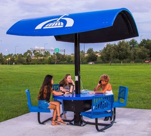 People at a blue picnic table under a fiberglass shade canopy in a park